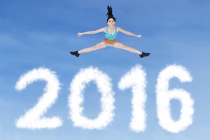 Image of pretty young woman with sportswear jumping on the air above clouds shaped numbers 2016